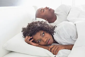 man snoring with woman having trouble sleeping